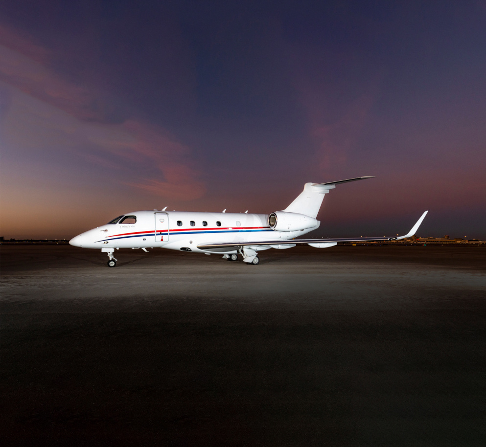 White private jet with blue and red accents parked at night with shiny new white paint